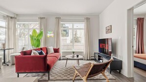 Una sala de estar con un sofá rojo, una mesa de centro, un televisor y un ventanal grande.