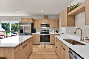 Eine moderne Küche mit Edelstahlgeräten, Holzschränken und einer großen Kochinsel mit Spüle.