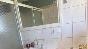 Une salle de bain avec un lavabo, des toilettes et un meuble de rangement, le tout de couleur blanche.