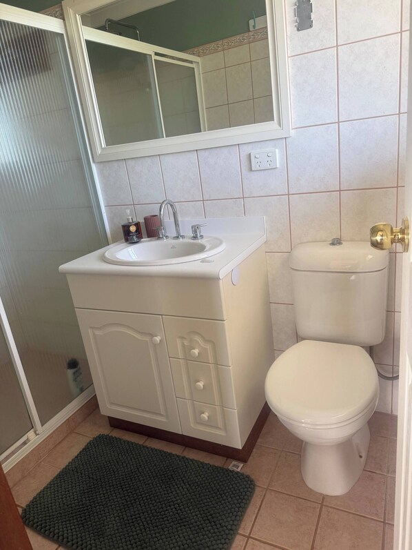 A bathroom with a white sink, toilet, and cabinet.