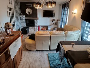 A living room with a stone fireplace, a television, a sofa, and a dining area with a table. - Provencal house with swimming pool and spa. (Ris)