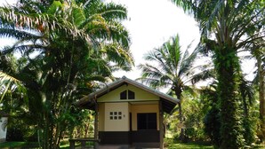 A small, single-story house with a sloped roof, surrounded by lush greenery and palm trees. - 057 resort (Sikao)
