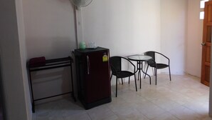 A small room with a refrigerator, a microwave, a table with two chairs, and a ceiling fan. - 057 resort (Sikao)