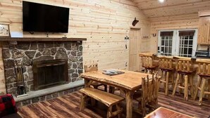 Ein Holzinterieur mit Kamin aus Stein, einem Holztisch und Barhocker.