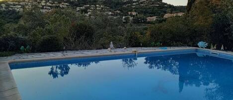 A swimming pool with a clear view of a hillside in the background.