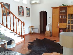 A living room with a staircase, a wooden cabinet with glass doors, and a large black rug. - Villa for 4 guests with private pool and terrace, in a peaceful setting – La Londe-les-Maures (LA LONDE LES MAURES)