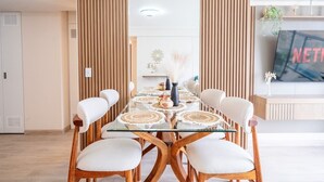Zona pranzo moderna con tavolo in vetro, sedie bianche e un elemento decorativo al centro.
