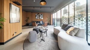 A modern living room with a sofa, ottoman, and coffee table, large windows, and a city view. - Largest & Elegant Apartment | Larco | Miraflores (Miraflores)