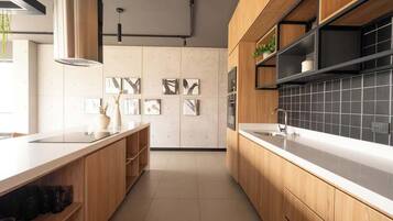 Una cucina moderna con mobili in legno, un piano di lavoro bianco e uno schienale piastrellato nero.