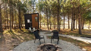 A cabin with a fire pit, two chairs, and a table with outdoor seating.