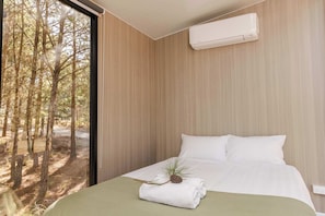 Een slaapkamer met een bed, een raam en een airconditioning.