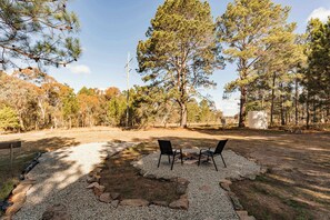 A campsite with two chairs, a fire pit, and a gravel path.