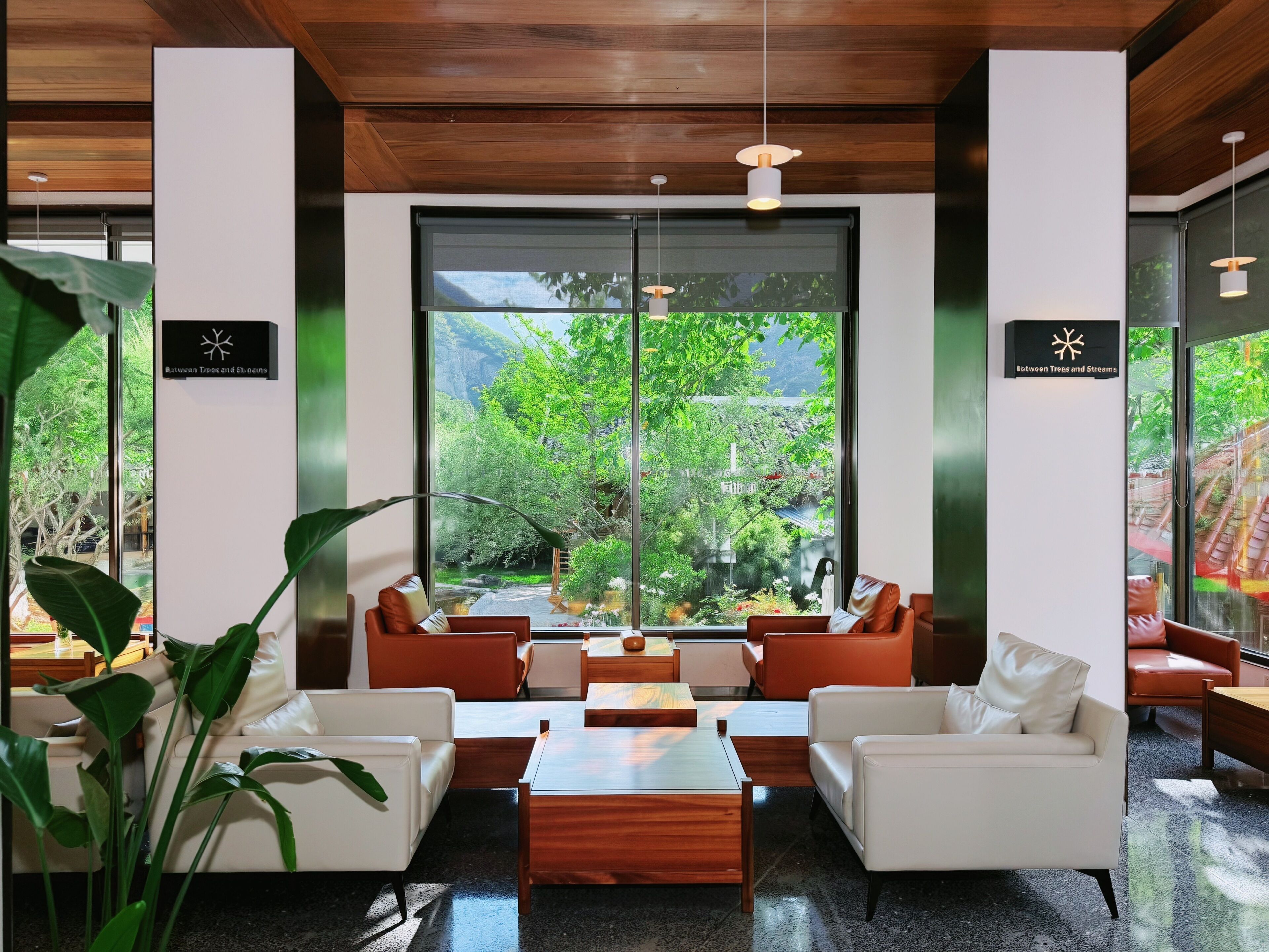 A modern interior with a seating area, large windows, and wooden ceiling.