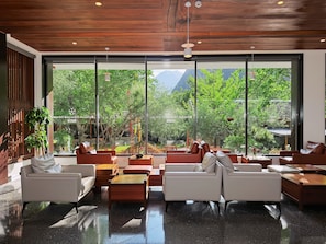 A modern interior with large windows, wooden ceiling, and seating arrangements. - Between Trees and Streams (Ngawa Autonomous Prefecture)