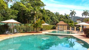 A clear swimming pool surrounded by lush greenery and a few buildings. - Splash at Sapphire - Pet Friendly, Resort Pool, Beachfront (Coffs Harbour)