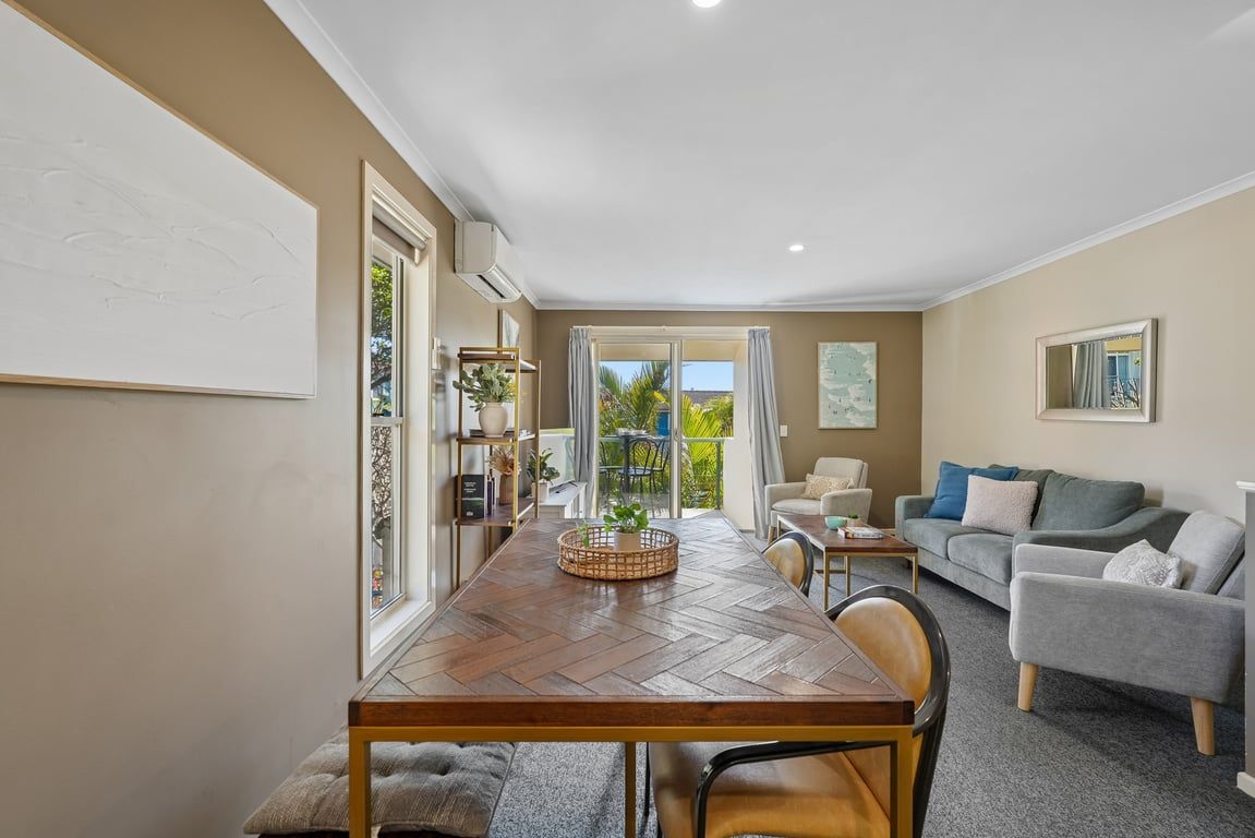 A dining area with a wooden table, chairs, and a view of the outdoors through a glass door.