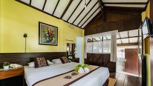A hotel room with a bed, a painting, a mirror, a TV, and a window with curtains. - Dedaunan Guesthouse (Batu)