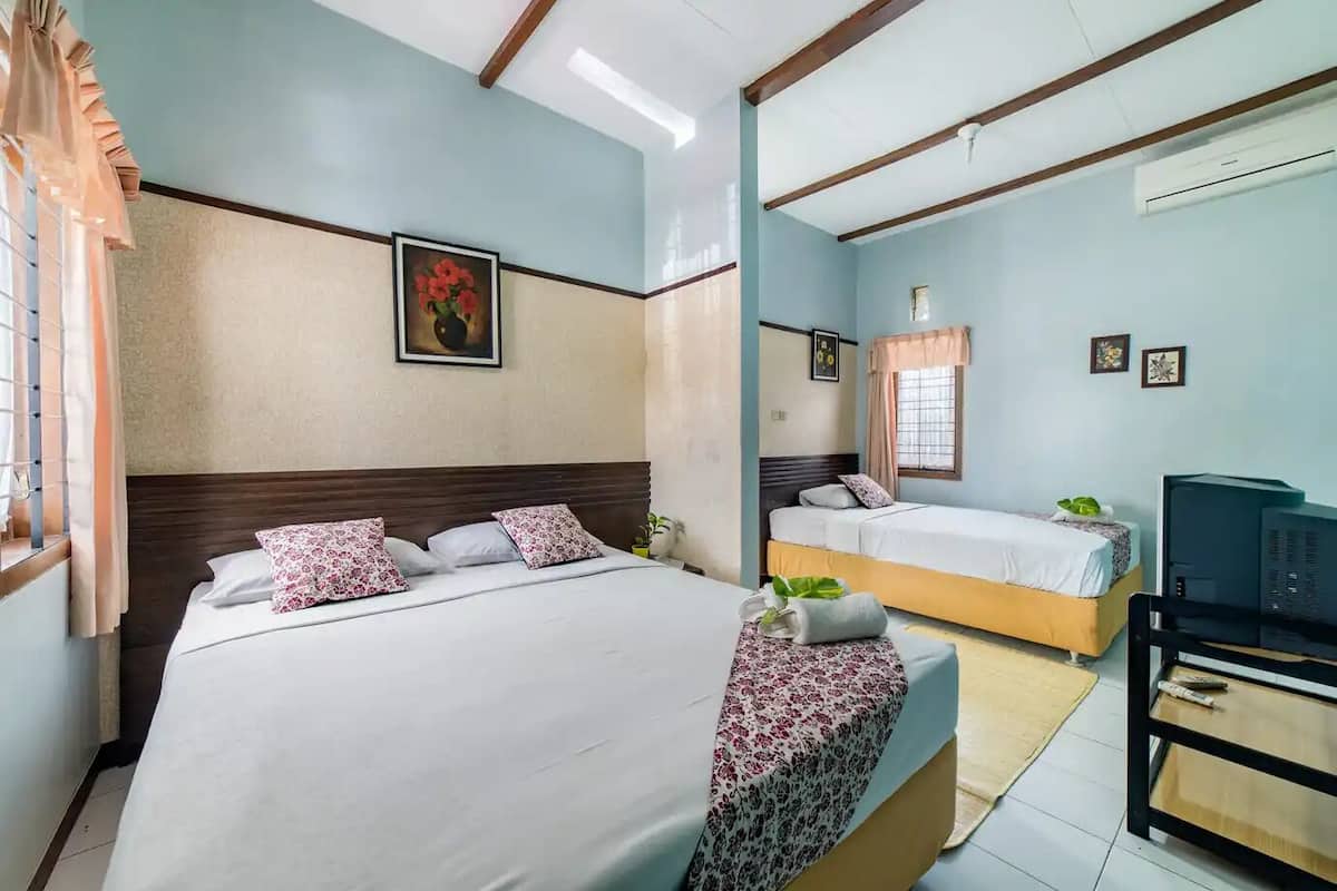 A hotel room with a large bed, a smaller bed, a TV, and a desk.