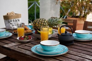 Una mesa de madera con alimentos para el desayuno, como frutas, pasteles y bebidas.