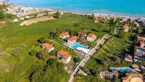 Ein Luftbild einer Küstenlandschaft mit einem großen Schwimmbecken, mehreren Gebäuden und freiem Blick auf das Meer.