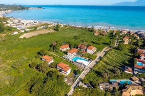Vista aèria d'una zona costanera amb una piscina grans, diversos edificis i una vista clara del mar.