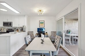 Et moderne køkken med hvide skabe, en mikroovn og et spiseområde med et bord og stole.