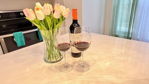 Un comptoir de cuisine orné d’un vase de tulipes, d’une bouteille de vin et de deux verres à vin.