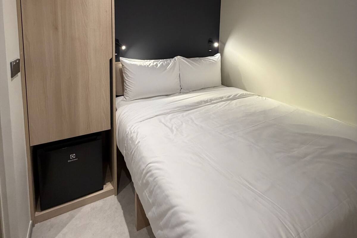 A bedroom with a bed, a wardrobe, and a wall-mounted light fixture.