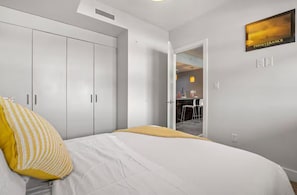 Une chambre à coucher avec un lit, une armoire, une porte donnant sur une salle de bain et une affiche motivante accrochée au mur.