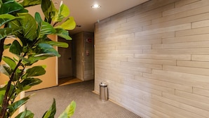 A hallway with a tiled floor, a trash bin, and a plant. - Studio Climatizado a 100m da Esta o Pinheiros (São Paulo)