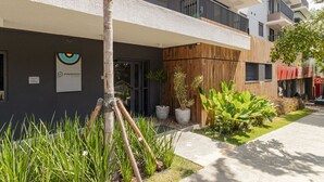 A modern building with a sign for 'PINHEIROS' on the facade, a wooden wall, and a small garden area with potted plants. - Studio Climatizado a 100m da Esta o Pinheiros (São Paulo)