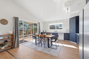 Eine moderne Küche mit Essbereich, großen Fenstern und Blick ins Freie.