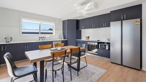 Eine moderne Küche mit dunklen Schränken, einem Holztisch und einem eingebauten Backofen.