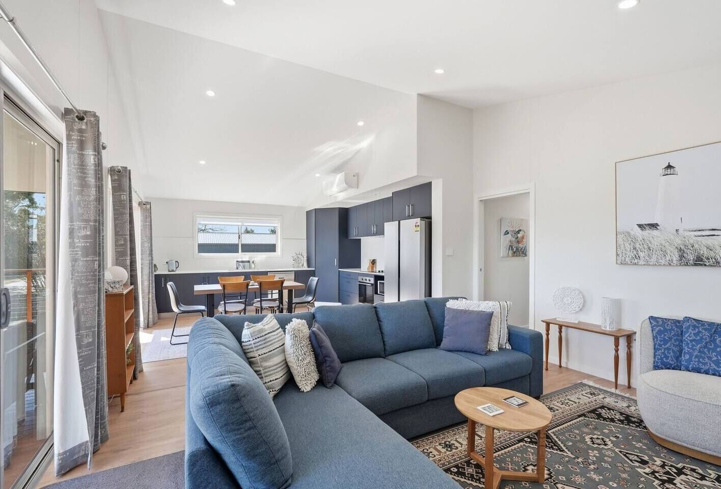 Un salon moderne avec un canapé gris, une petite table basse en bois et un coin repas comprenant une table et des chaises.