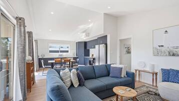 Un salon moderne avec un canapé gris, une petite table basse en bois et un coin repas comprenant une table et des chaises.
