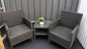 Deux chaises en osier et une petite table agrémentée d’une plante en pot, le tout placé sur un balcon.