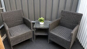 Two wicker chairs and a small table with a potted plant in a balcony area. - Private Coastal Studio - King Bed - Courtyard - Fully Detached - Seacliff Beach (Seacliff)