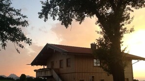 Une maison en bois à deux étages, avec un toit en pente et un escalier menant à l’étage supérieur.