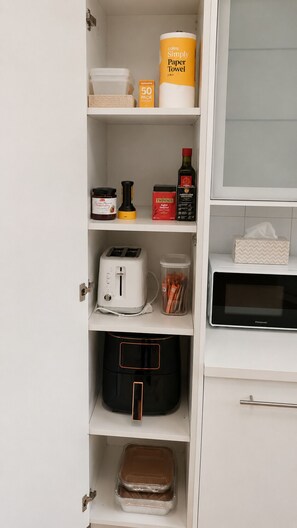 Eine Küche mit Toaster, Mikrowelle, Kaffeemaschine und Mülleimer.