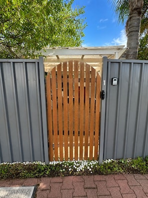 Een omheinde toegang met een houten poort, een metalen poort en een bord met het nummer 1.
