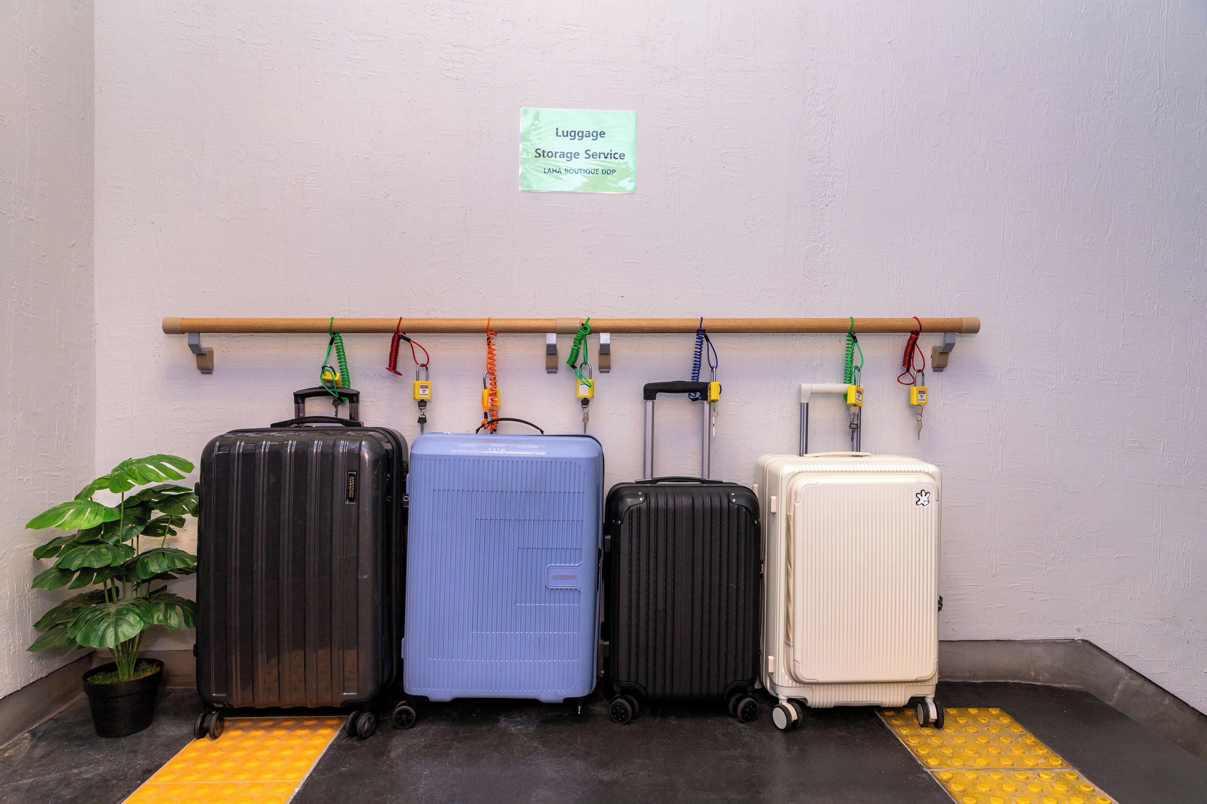 A luggage storage service area with a sign, a wooden rack, and four suitcases.