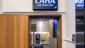 L’entrée d’un hôtel, avec une enseigne indiquant : « LAHA BOUTIQUE DDP 3F ».
