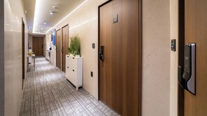 Un couloir d’hôtel avec des portes en bois, un comptoir de réception et une plante.