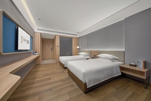 A hotel room with two beds, a TV, a desk, and a wardrobe.