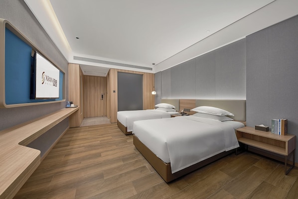 A hotel room with two beds, a TV, a desk, and a wardrobe.