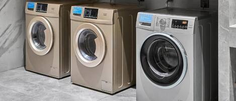 Three washing machines under a shelf with labels in a tiled room.