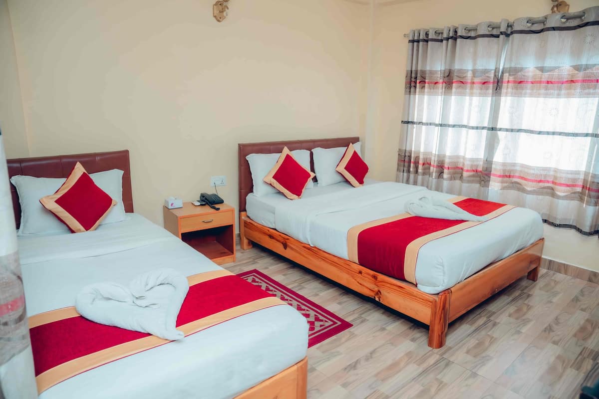 A hotel room with two beds, a nightstand, and a window with curtains.