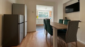 A modern kitchen with a refrigerator, dining table, and chairs. - Eye Road Retreat (Peterborough)