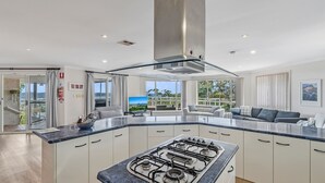 Een moderne keuken met een gasfornuis, witte kasten en een groot raam met uitzicht op de omgeving.