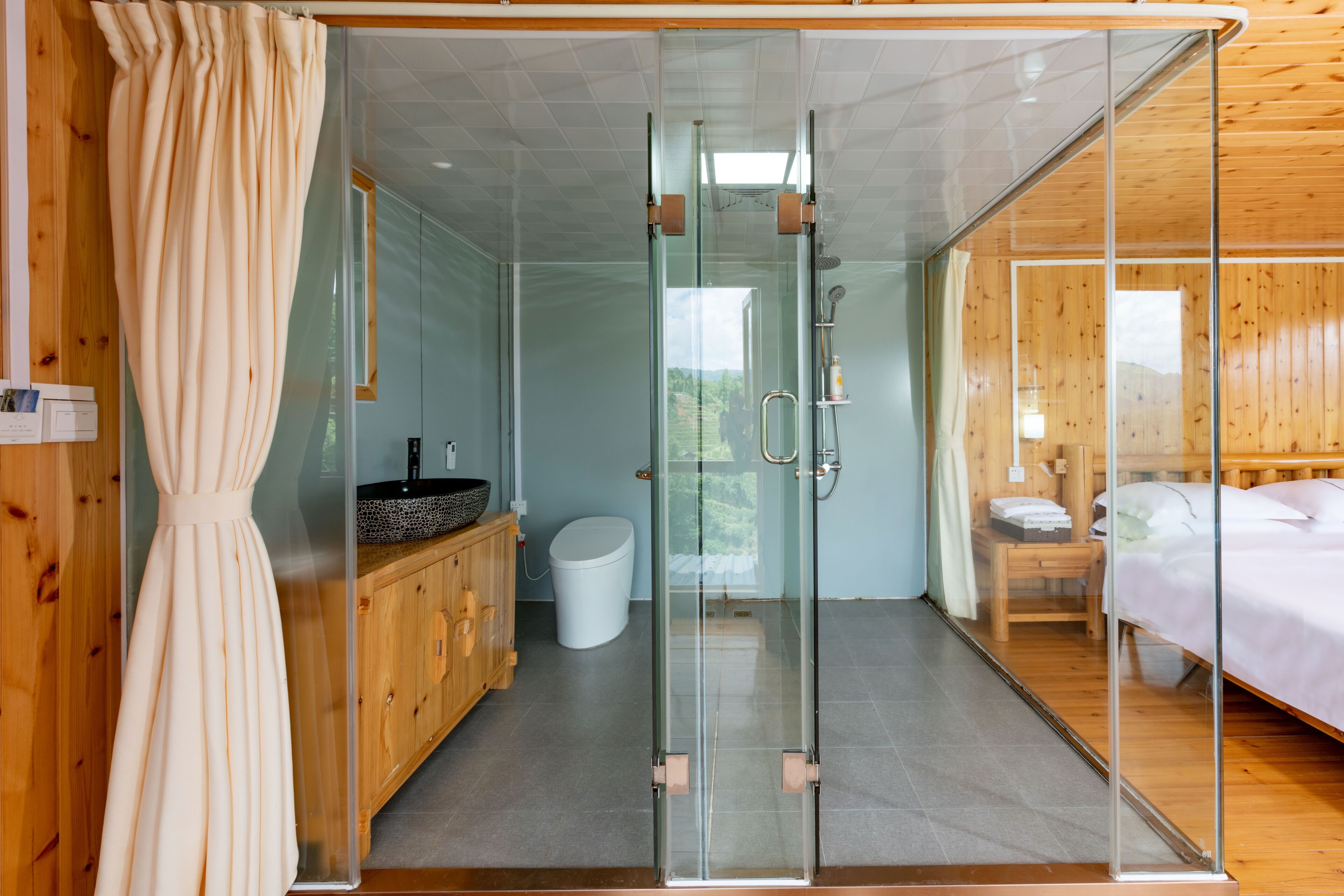Un baño moderno con cabina de ducha de vidrio, muebles de madera y un inodoro a la vista.